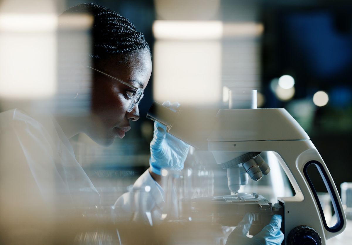 A scientist views slides through a microscope